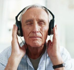 Senior man wearing headphones, eyes closed, close-up