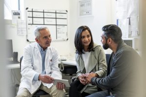 Young couple talking with male doctor in office
